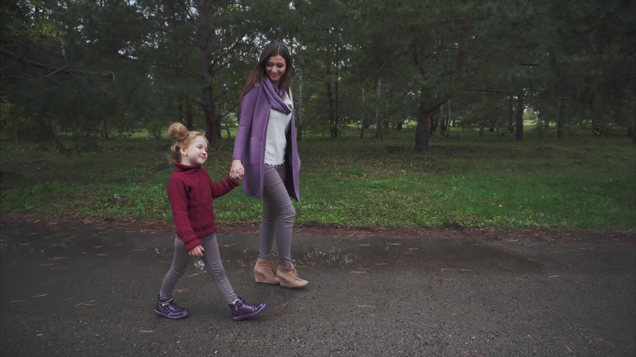 Moeder en dochter wandelen in een park op een regenachtige dag