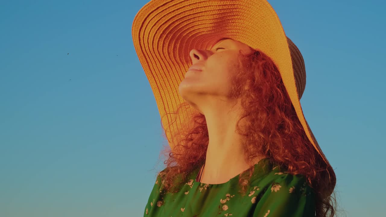 Woman in a straw hat enjoying the sunset