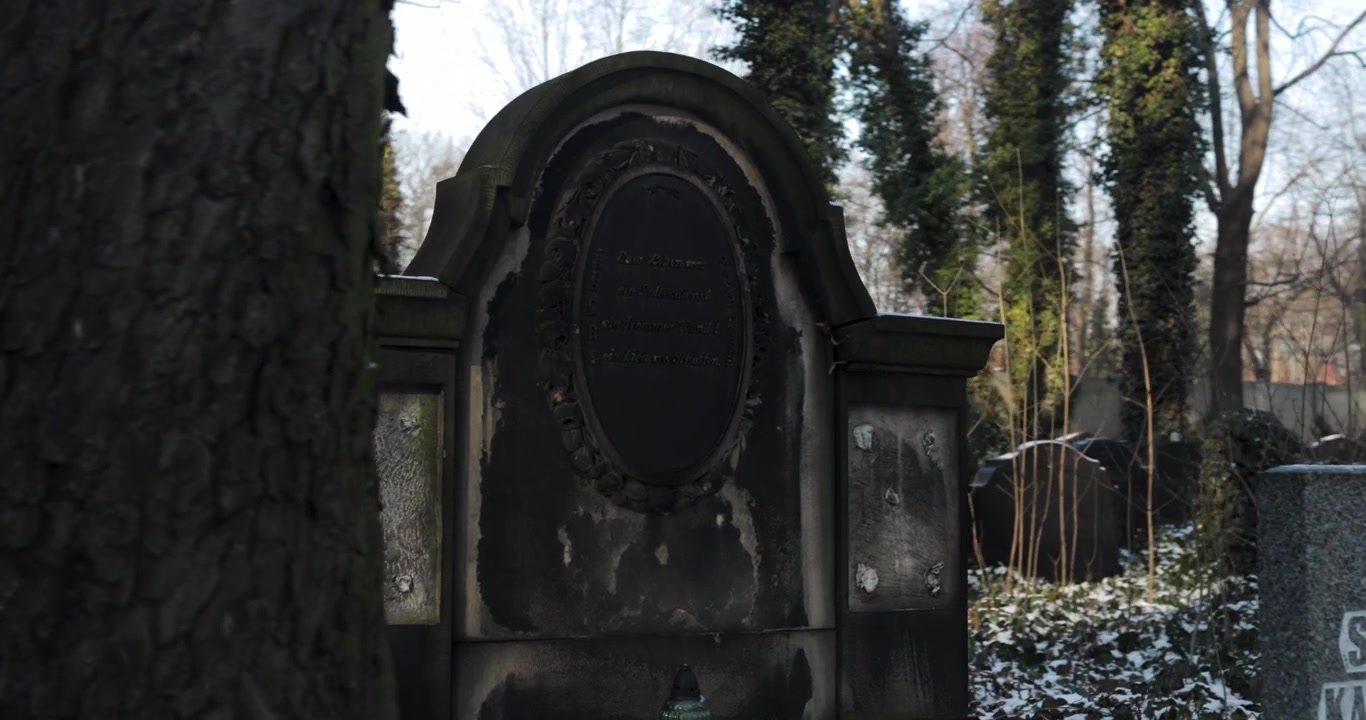 Monumentální náhrobek na židovském hřbitově v zimě za jasného dne, zachycený v dynamickém 4K záběru.