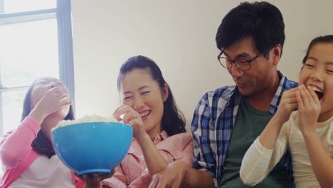 family watching tv while having popcorn in living room 4k