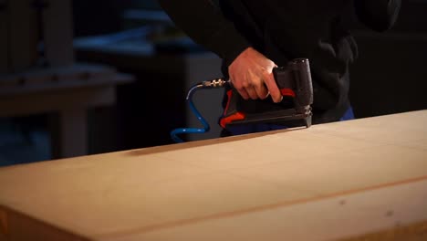 persona que utiliza una pistola de clavos para montar un panel de madera
