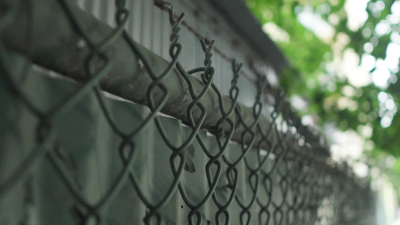 el alambre de púas afilado se extiende a través de la parte superior de una red verde y una valla de acero corrugado, que se erige como un límite resistente