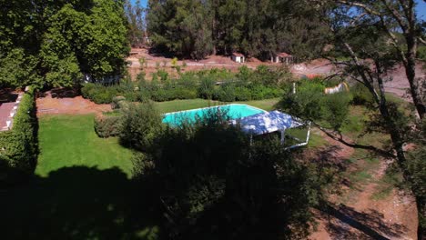 blue in-ground pool sits in manicured lawn garden area behind classic portuguese estate home