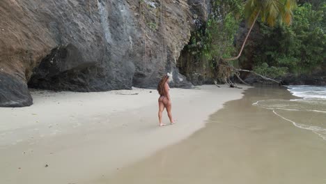 Vista-De-Drone-De-Una-Chica-En-Bikini-Caminando-Sobre-La-Arena