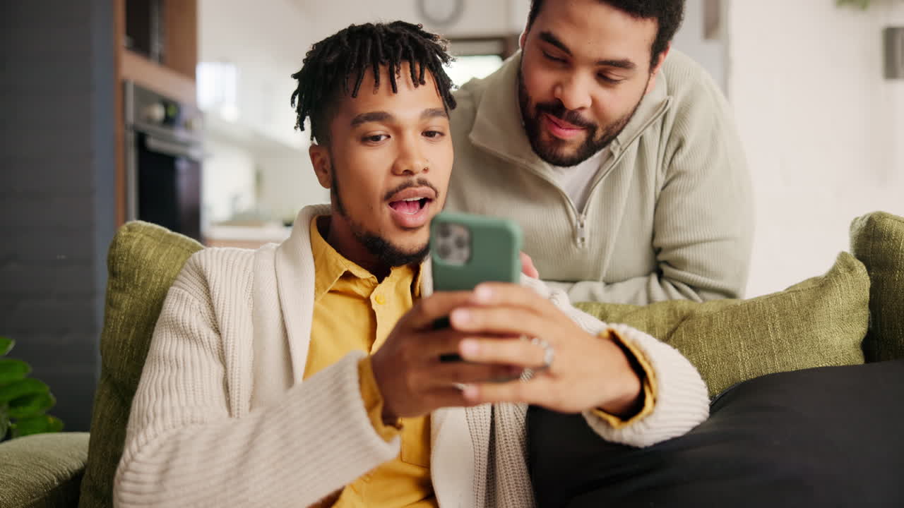 dos hombres mirando un teléfono inteligente en un sofá