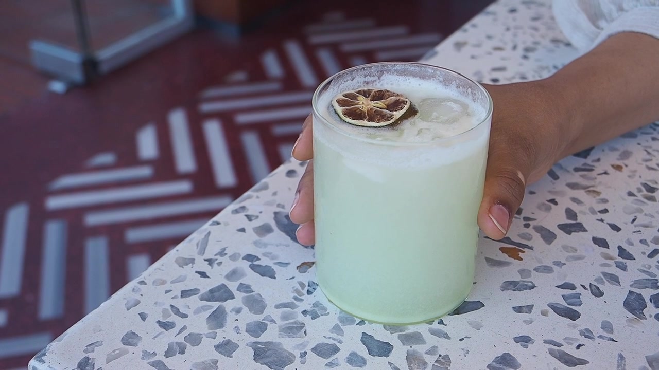 Hand Picking Up a Refreshing Cocktail from a Terrazzo Bar Counter