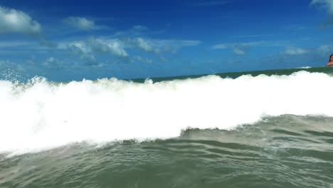 gente buceando bajo una ola en formación a medida que se acerca a la hermosa playa praia do madeiro en el noreste de brasil en rio grande do norte