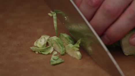 cutting brussels sprout with knife on wooden board