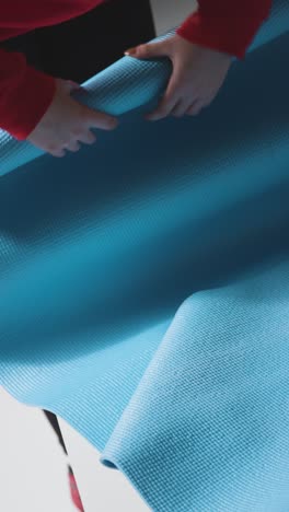 vertical shot of a girl rolling up mat