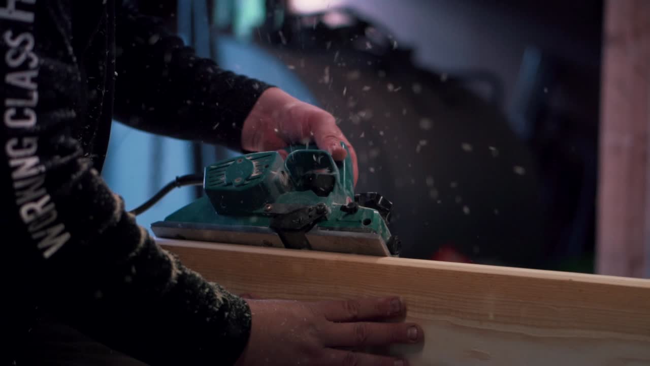 Carpenter planes a wooden plank  to get rounded edges.