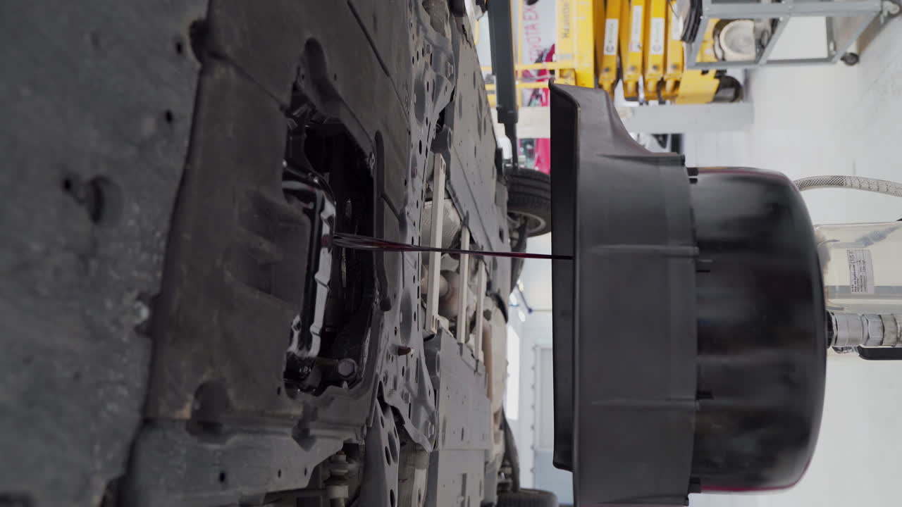 aceite de motor de automóvil usado que cae en el recipiente durante el servicio de cambio de aceite en el taller