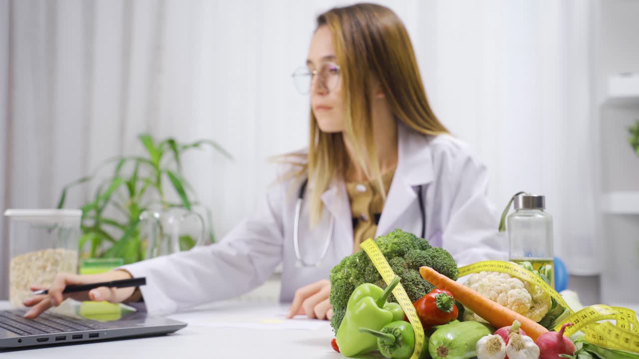 mujer nutricionista trabajando en una computadora portátil y preparando planes de alimentación saludable.