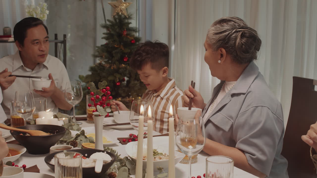 Grandma Putting Food in Plate of Grandson during Family Dinner