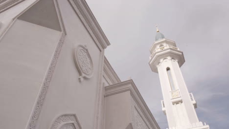 white mosque with minaret and ornamental facade