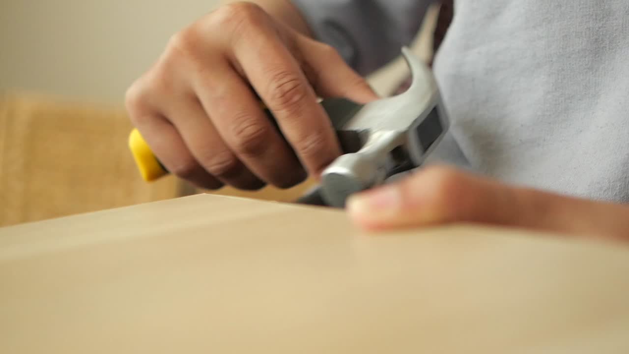 Person using a hammer to fix a piece of wood