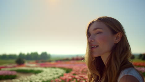 Portrait-of-smiling-woman-in-sunlight.-Happy-girl-enjoying-nature-in-flower-park