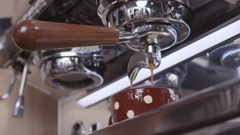 idyllic slow-motion close-up of an industrial coffee maker pouring fresh coffee in a cup to keep up with the routine