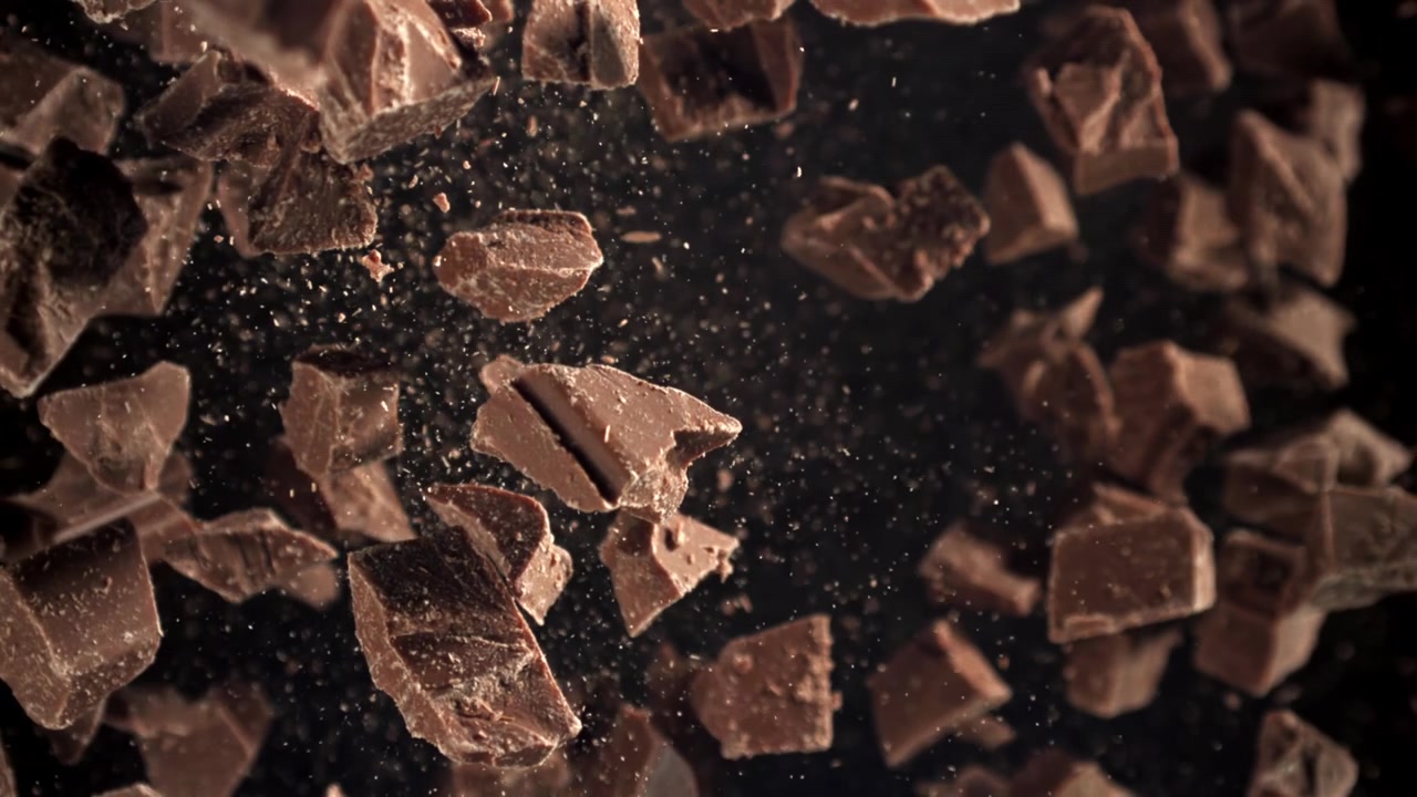 Pedaços de Chocolate Caindo em Câmera Lenta em um Fundo Escuro