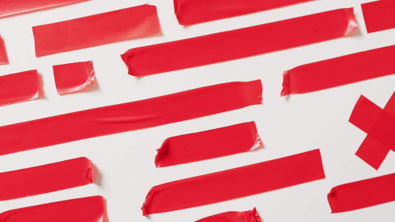 ⁇ 색 배경에 여러 개의 빨간 테이프 조각의 클로즈업 비디오