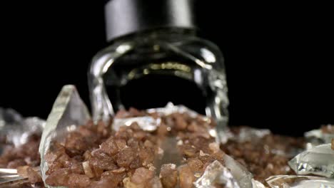 Pulling-away-from-a-broken-sea-salt-grinder,-the-focus-and-magnification-in-the-foreground-to-highlight-salt-and-glass-textures