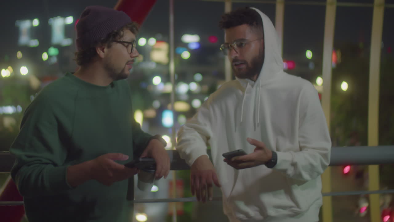 Friends Using Phones and Chatting at Night in Big City