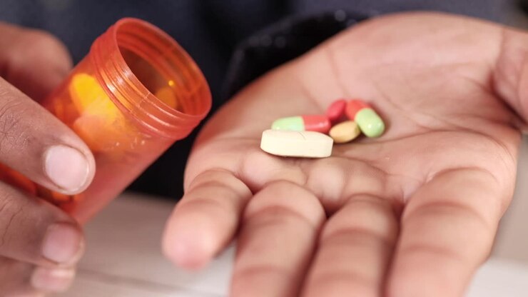 Person holding pills and bottle