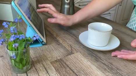mujer irreconocible usando tableta bebiendo café en casa