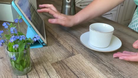 unrecognizable woman using tablet drinking coffee at home