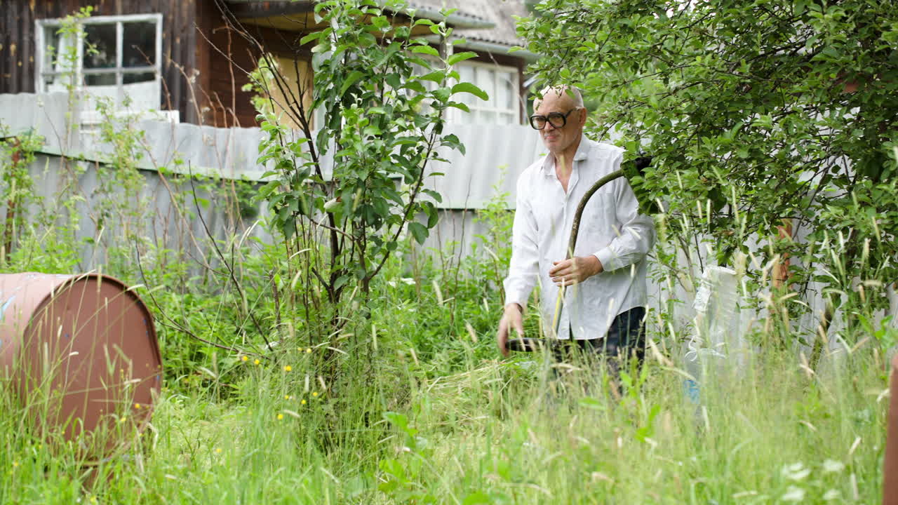 старик стрижет траву с помощью электрической косилки
