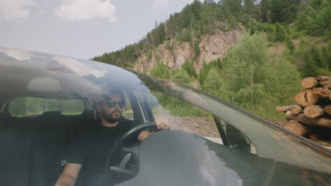 young man driving in a cutted trees deposit area in the mountains