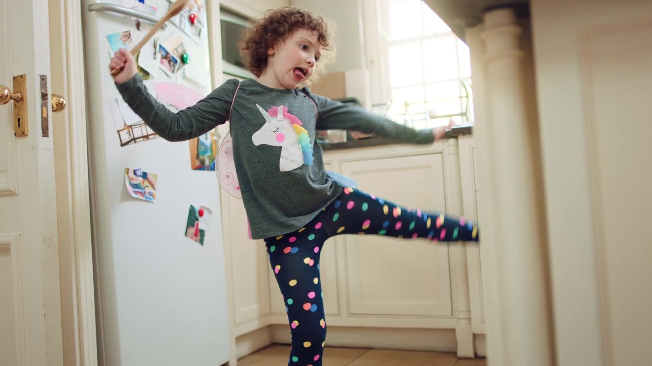 Little Girl Wearing Fairy Wings Dancing in the Kitchen