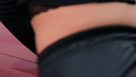 Close-up-of-a-woman's-hand-with-on-a-dusty-red-car