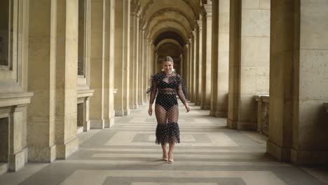 woman in a polka dot dress walking through a parisian archway