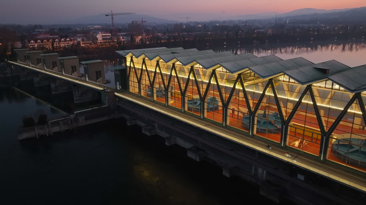 스위스 비르스펠덴에 있는 수력 발전소의 조명이 켜진 터빈 하우스와 함께 라인강에 반사되는 다채로운 하늘