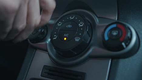 hand pressing dashboard buttons for car air conditioner fan and turning knobs for heat and air intake settings in slowmo