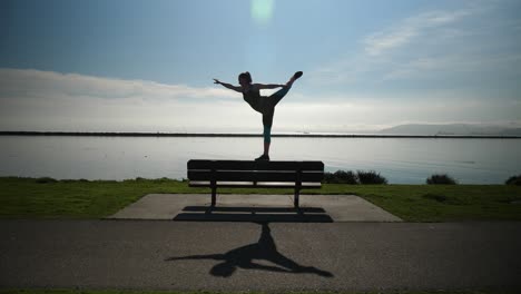 young girl walks on park bench like a balance been and does swan pose