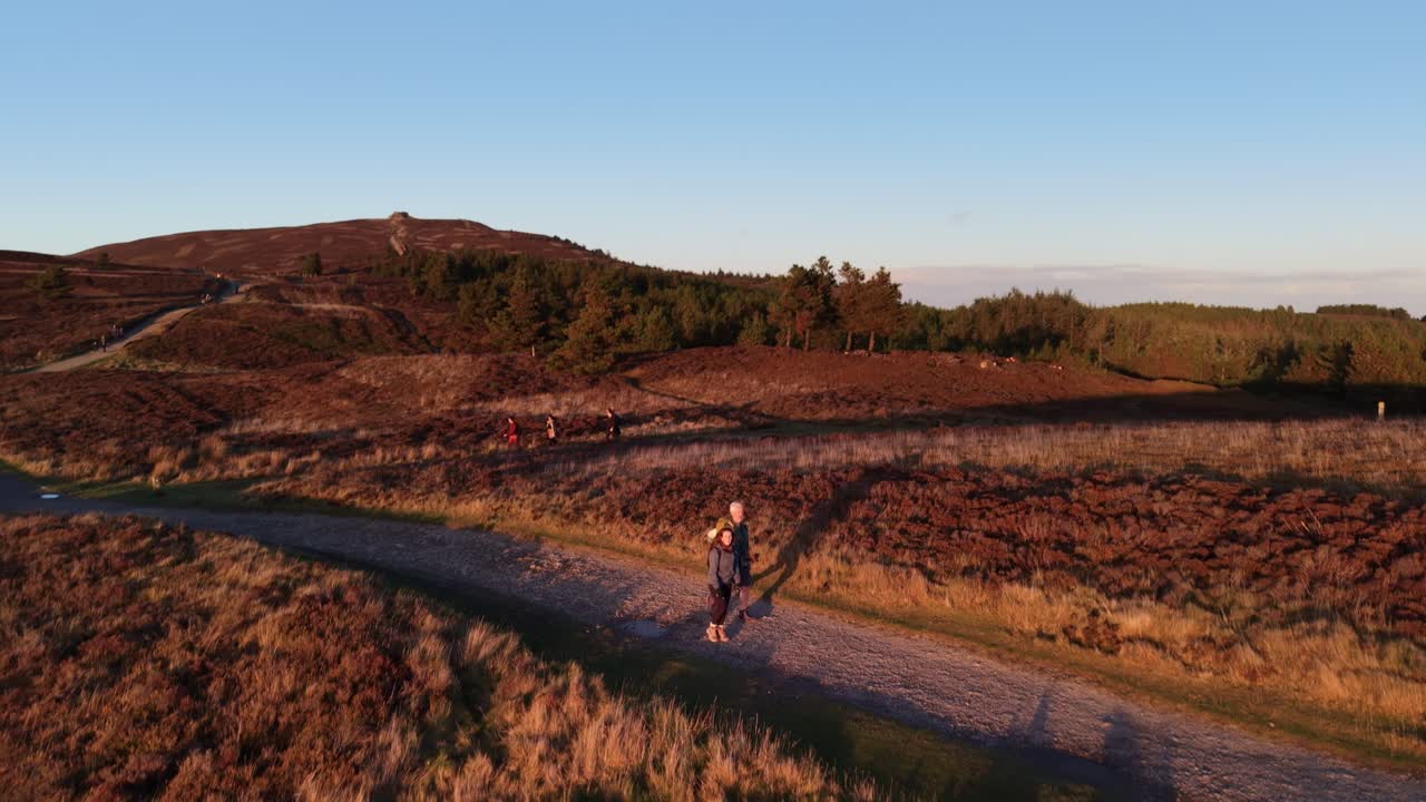Hikers walking the Moel Famau trail at sunset in slow motion in stunning HDR , North Wales, UK - drone rotate revealing scenery