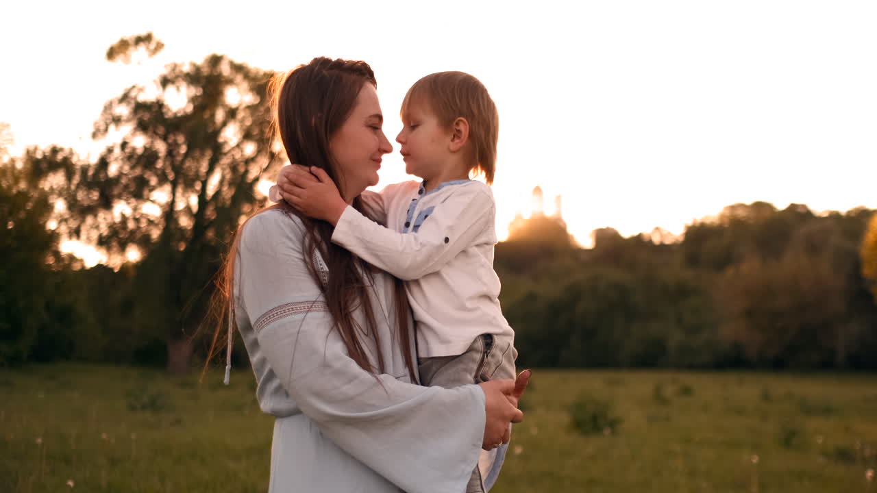 Madre e figlio affettuosi che si abbracciano all'aperto al tramonto durante la loro vacanza estiva.