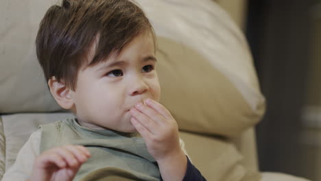 Lindo-Bebé-Asiático-Comiendo-Nueces-En-Una-Silla-Alta