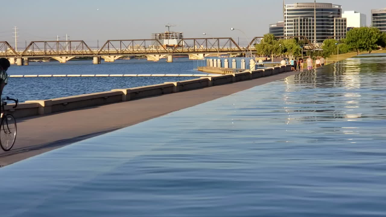 Man riding a bicycle with Tempe Town lake on left and water feature on right in Tempe, Arizona