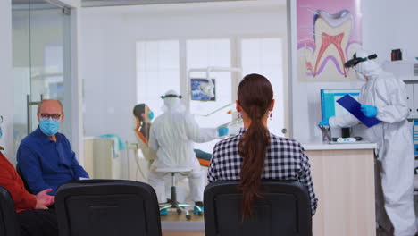 enfermera dental con traje de protección y clipboard saliendo de la recepción