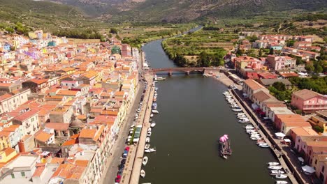 Flyover-aerial-shot-of-river-Temo-in-picturesque-town-of-Bosa,-Sardinia,-summer