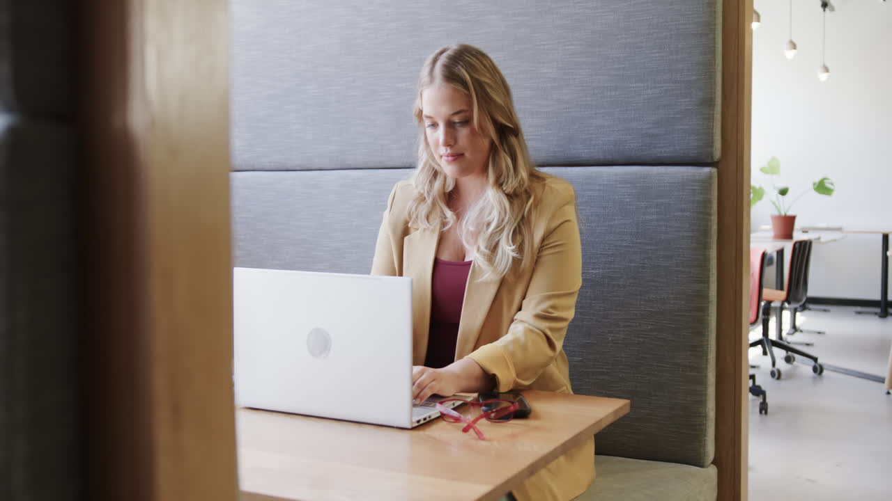 retrato de una feliz mujer de negocios caucásica de tamaño plus usando una computadora portátil en el salón de la oficina