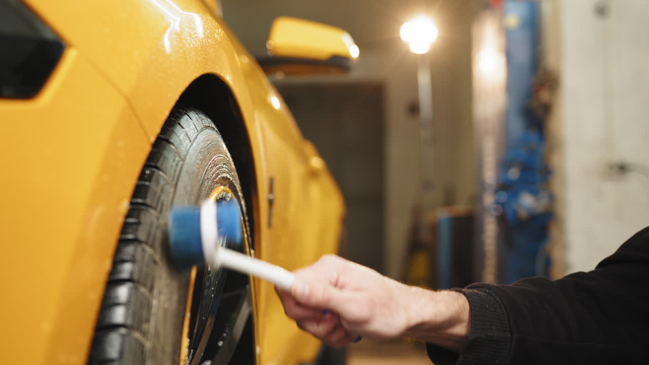 limpiando los neumáticos y la rueda de un coche amarillo