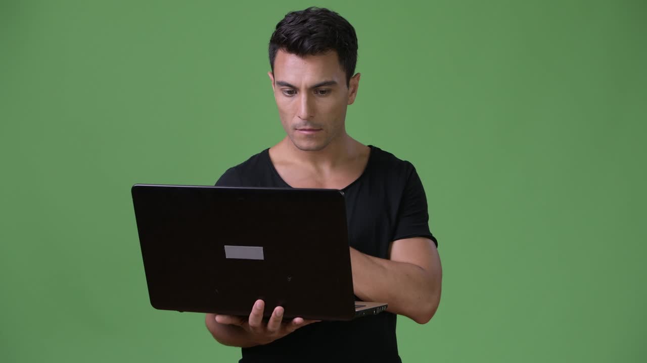 joven y guapo hombre hispano contra un fondo verde