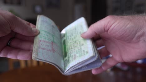 hombre mirando a través de sus páginas de pasaporte llenas de sellos de viaje y visados
