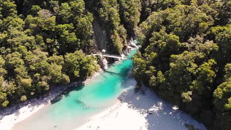 Swing-Bridge-Across-The-Famous-Blue-Pools-Of-Makarora-River-In-The-West-Coast,-New-Zealand-During-Mid-Day