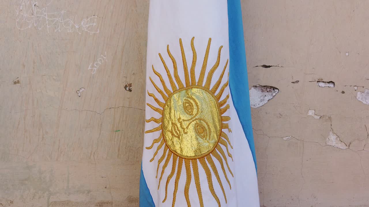 fotografía de cerca de la bandera nacional argentina con sol dorado en el poste de una escuela pública