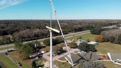 técnicos de grúas que instalan una torre de telefonía celular en forma de cruz