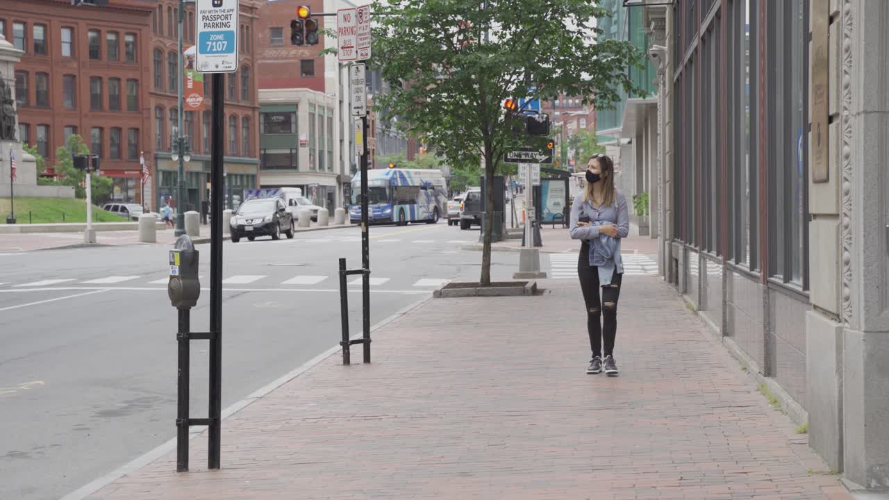 검은 얼굴 마스크를 쓴 소녀가 미국 전 세계적으로 유행하는 동안 황량한 거리를 걷고 있습니다.